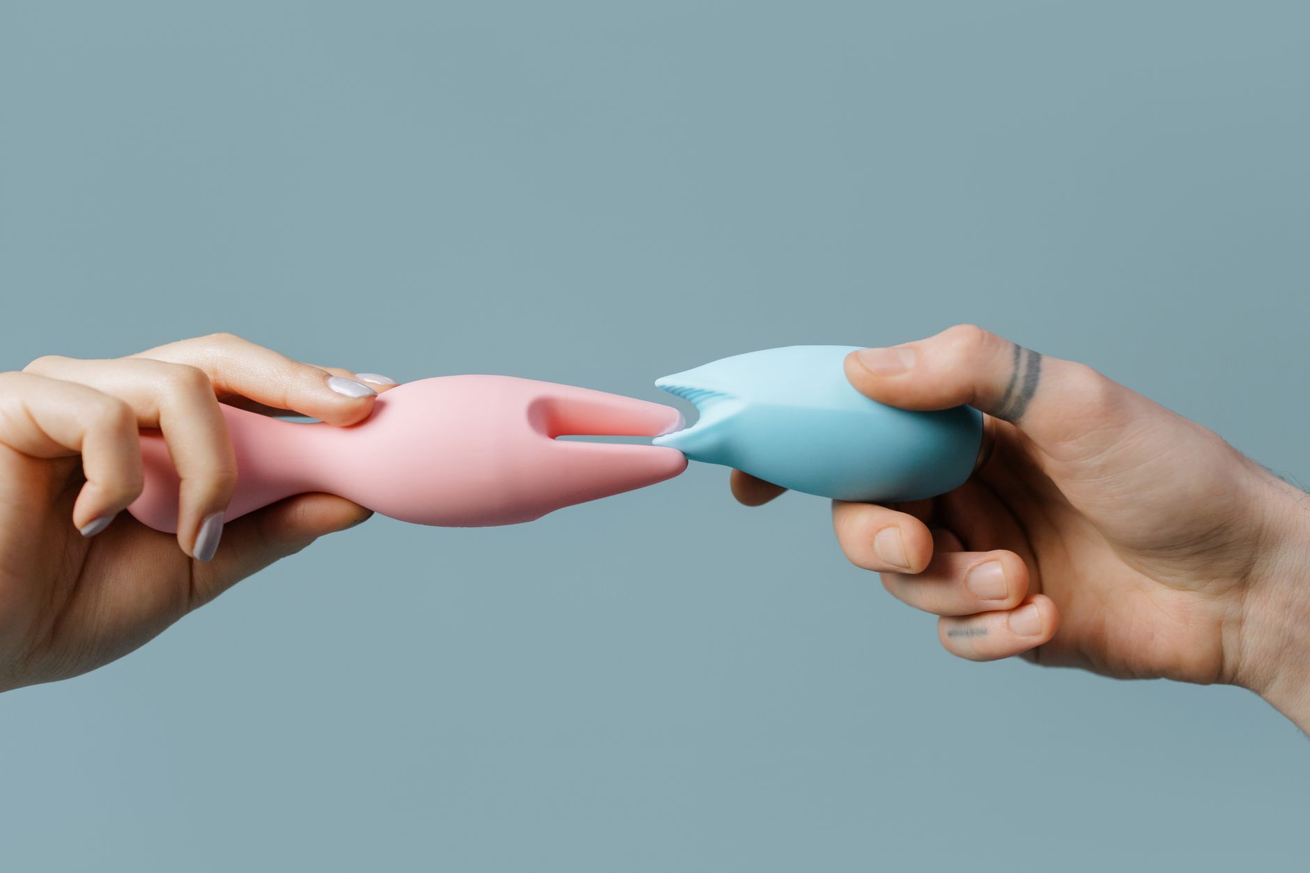 Hands holding pastel-colored silicone toys for adult wellness