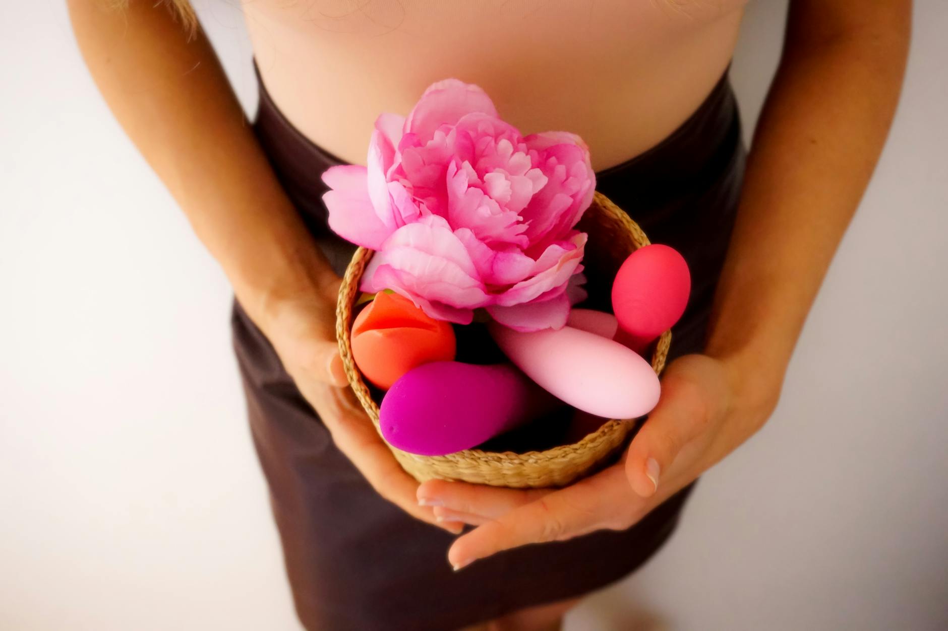 Woman in intimate moment holding a pink personal massager, surrounded by books, representing vulnerability and self-discovery